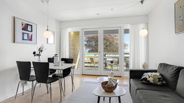 Un salon moderne comprenant un canapé, une table à manger avec des chaises et une grande fenêtre donnant sur un balcon.