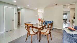 A modern living room with a dining area, featuring a wooden table and chairs, a sofa, and a kitchen in the background. - Modern East Hill Home, Premier Location! (Pensacola)