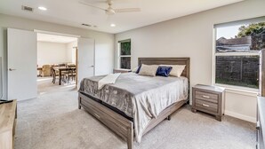 A bedroom with a bed, bedside tables, a ceiling fan, and a window. - Modern East Hill Home, Premier Location! (Pensacola)