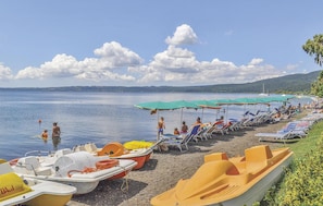 Una spiaggia con file di lettini e piccole imbarcazioni disposte a riva.