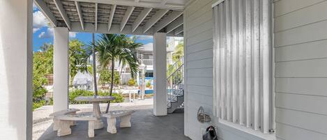 A covered porch with a concrete floor, two stone benches, and a small black dog sitting by the wall.