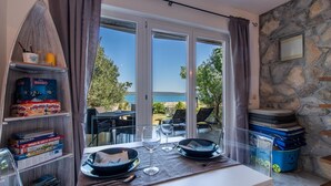 Habitació amb vista al mar, taula preparada amb plats i gots de vi, i prestatges amb jocs de taula.