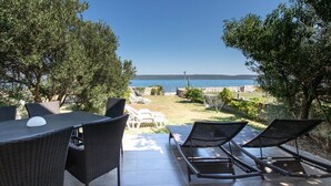 Terrassa a l'exterior amb mobles de vimet, una taula i vista al mar.