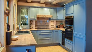 Una cocina moderna con armarios azules, una encimera de madera y hornos empotrados.