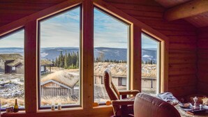 Una cabaña con ventanas amplias que ofrecen vistas de un paisaje montañoso.
