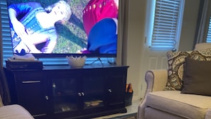Ein Wohnzimmer mit einer Couch, einem Fernseher und einem Hund.