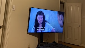 Ein Fernseher an der Wand in einem Zimmer mit Bett und Tür.