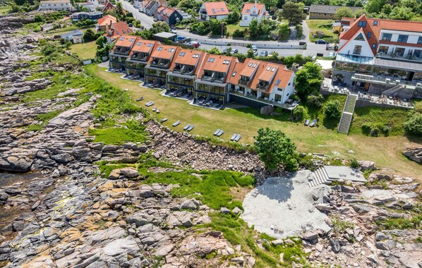 Ein Küstenhotel mit mehreren Gebäuden, einer felsigen Küstenlinie und einem Sandstrand.