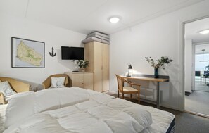 Ein Schlafzimmer mit Bett, Schreibtisch, Stuhl, Kleiderschrank, Fernseher und einer Karte an der Wand.