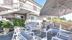 An outdoor patio area with white furniture, a large umbrella, and potted plants. - Lovely home in Viagrande (Viagrande)