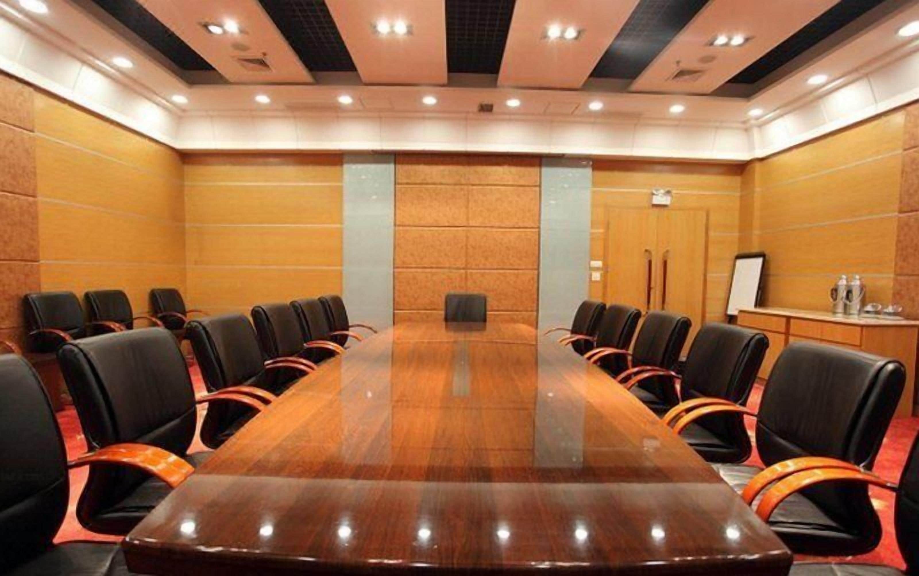 A conference room with a long table, black chairs, and a whiteboard.
