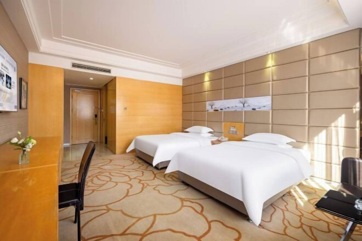 Habitación de hotel con dos camas, un escritorio y una silla.