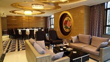 A hotel lobby with a dining area, sofas, and a chandelier.