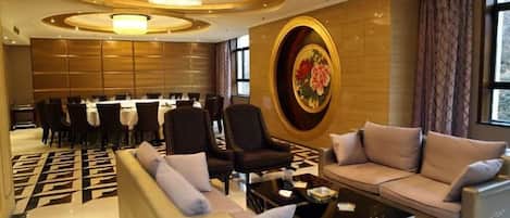 A hotel lobby with a dining area, sofas, and a chandelier.