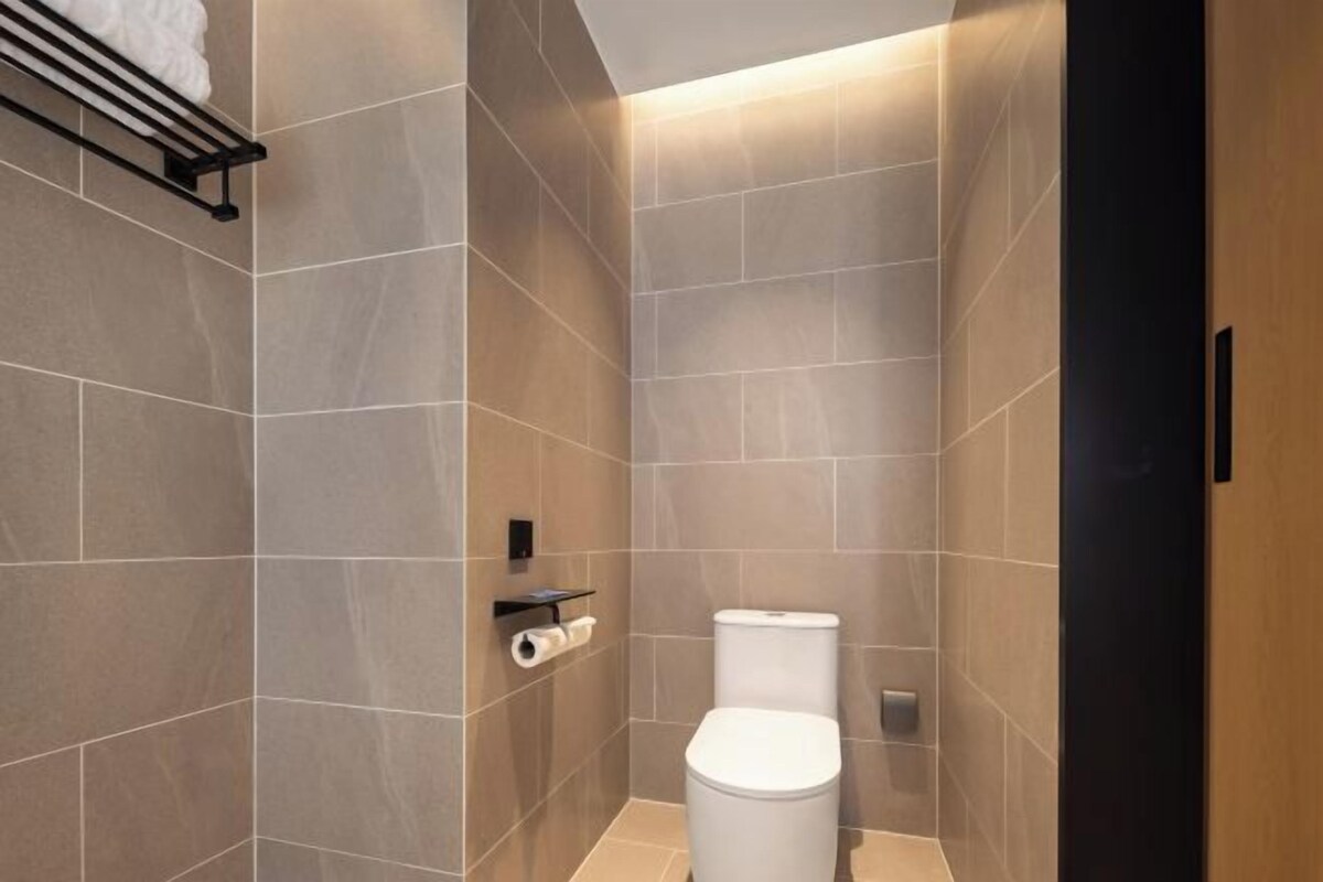 A modern bathroom with a toilet, a towel rack, and a toilet paper holder.