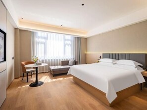 A hotel room with a bed, a desk, a chair, and a window with curtains. - Faguo Hotel (Dalian)