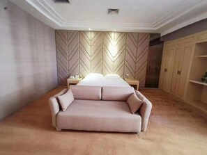 Une chambre à coucher avec un grand lit, un canapé, une armoire et une table de chevet.