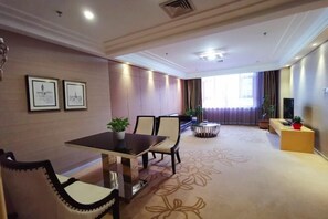 Une chambre d’hôtel comprenant un coin repas, un canapé, une table basse et un téléviseur.