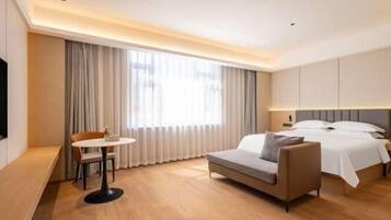 A hotel room with a bed, a sofa, a small table, and a TV.