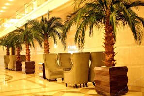 A lobby with a row of armchairs and palm trees. - Faguo Hotel (Dalian)