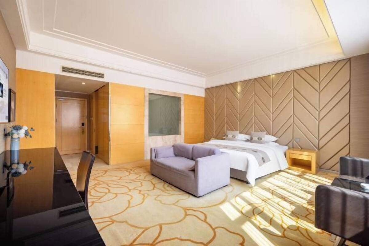 Habitación de hotel con cama, sofá, escritorio y piso alfombrado.