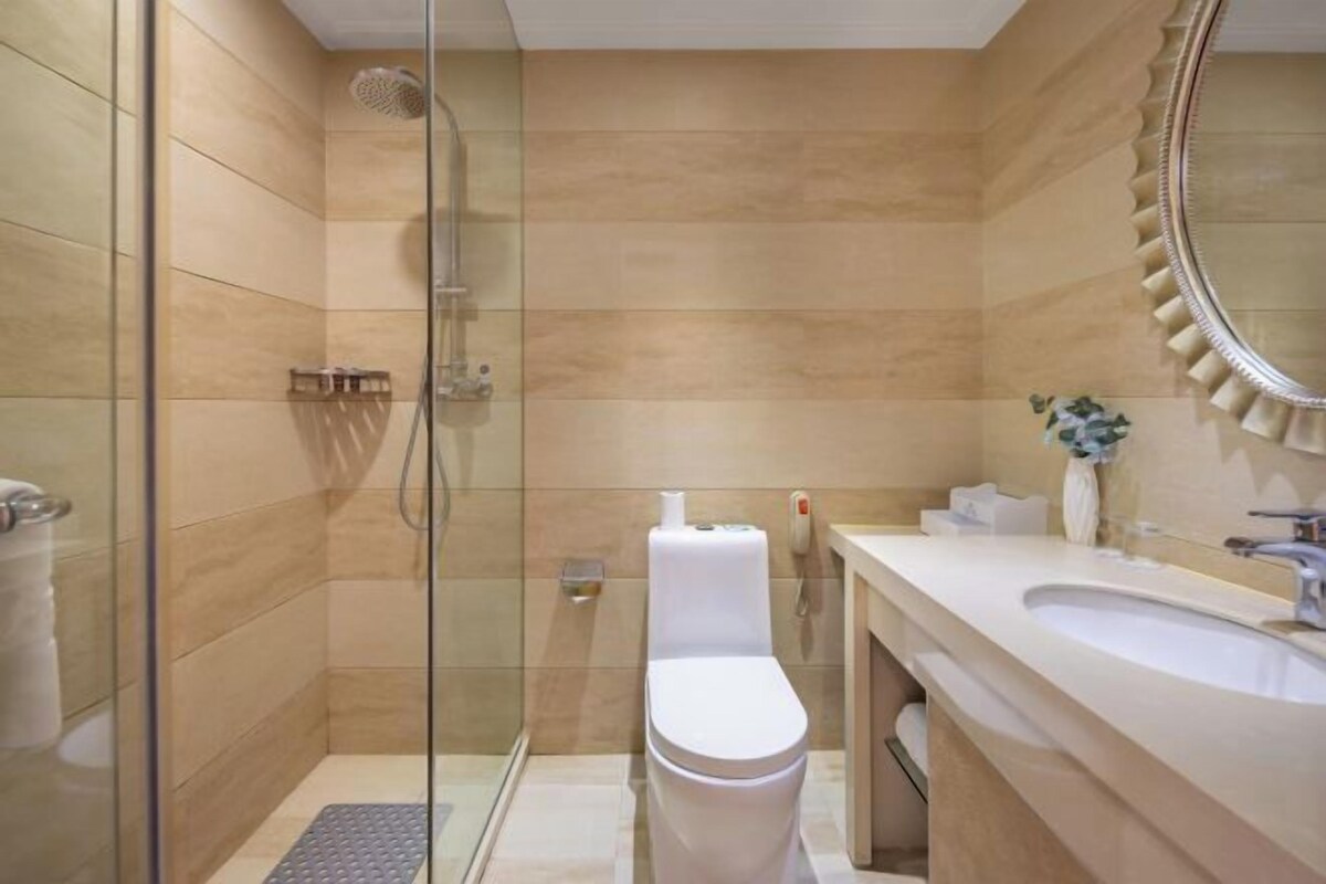 A modern bathroom with a glass shower enclosure, a white toilet, and a vanity with a sink and mirror.