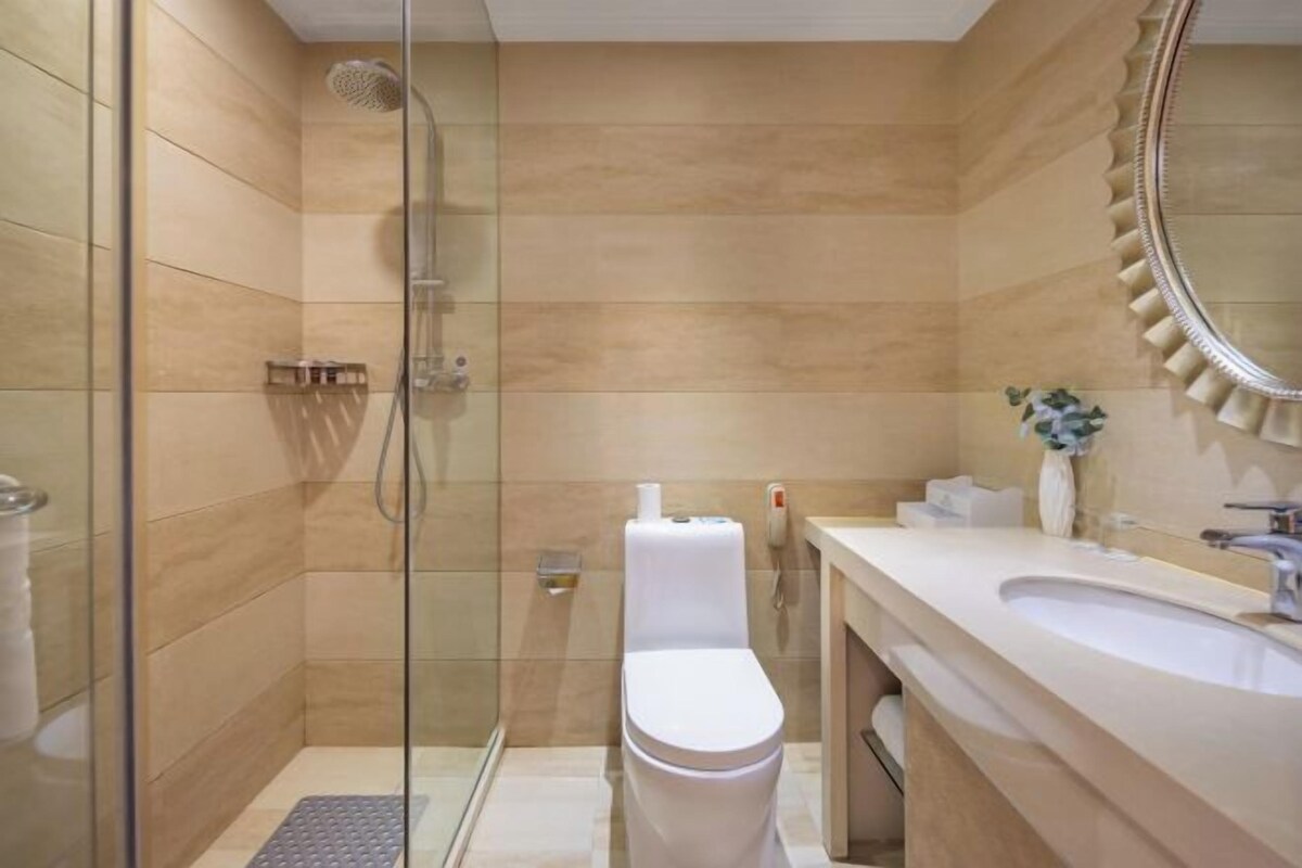 A modern bathroom with a glass-enclosed shower, a white toilet, and a vanity with a mirror.
