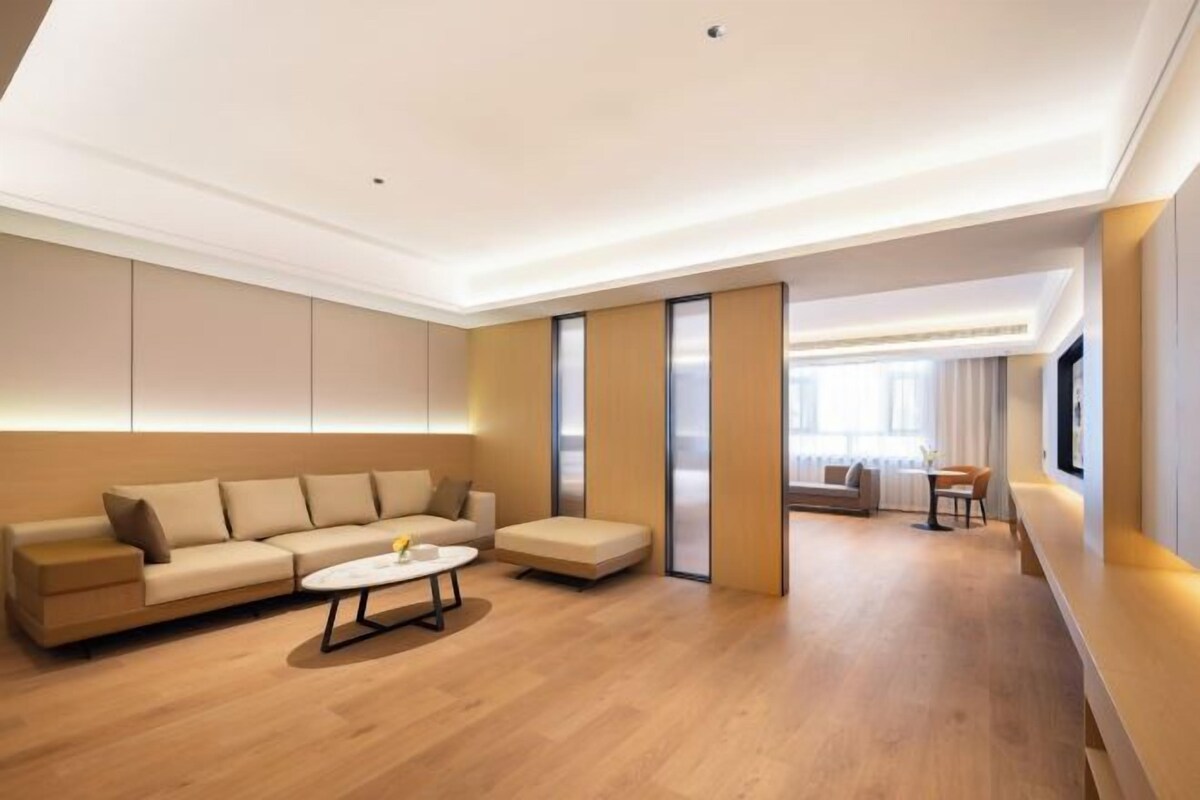 A modern living room with a sofa, a coffee table, and a small table with chairs.