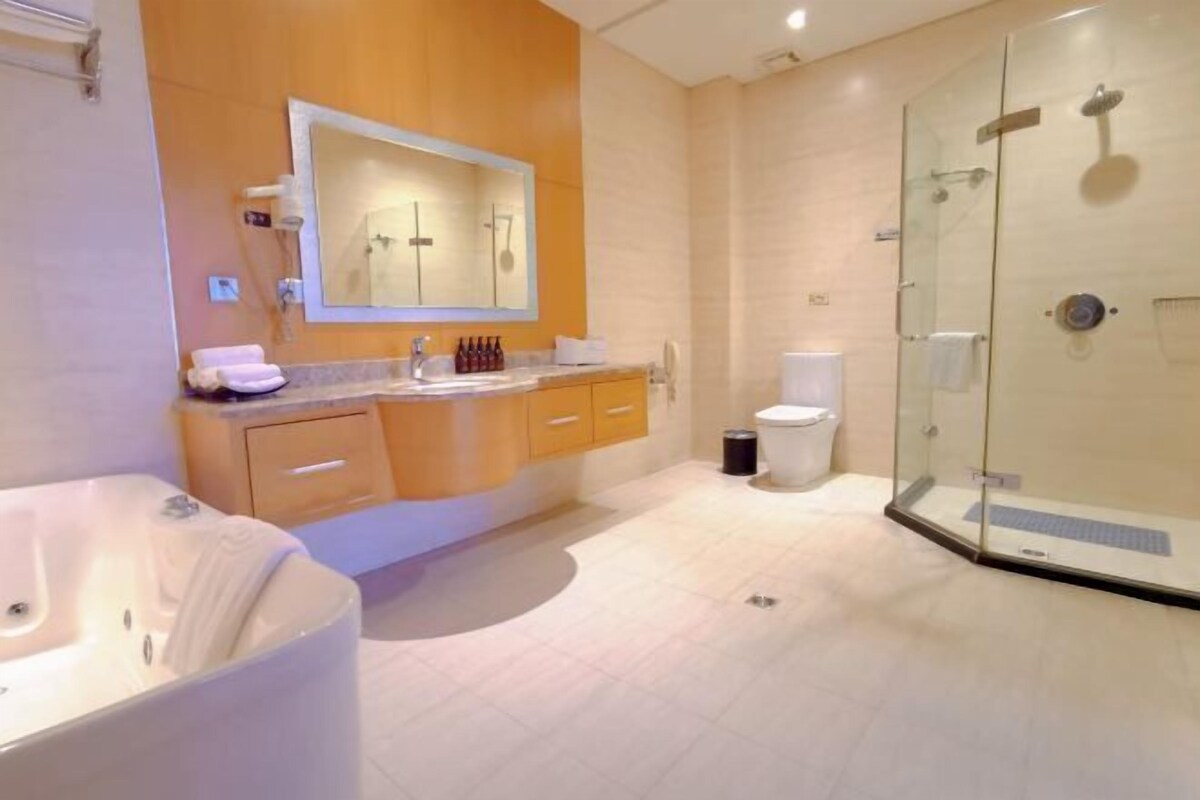 A modern bathroom with a glass shower enclosure, a large mirror, and a bathtub.