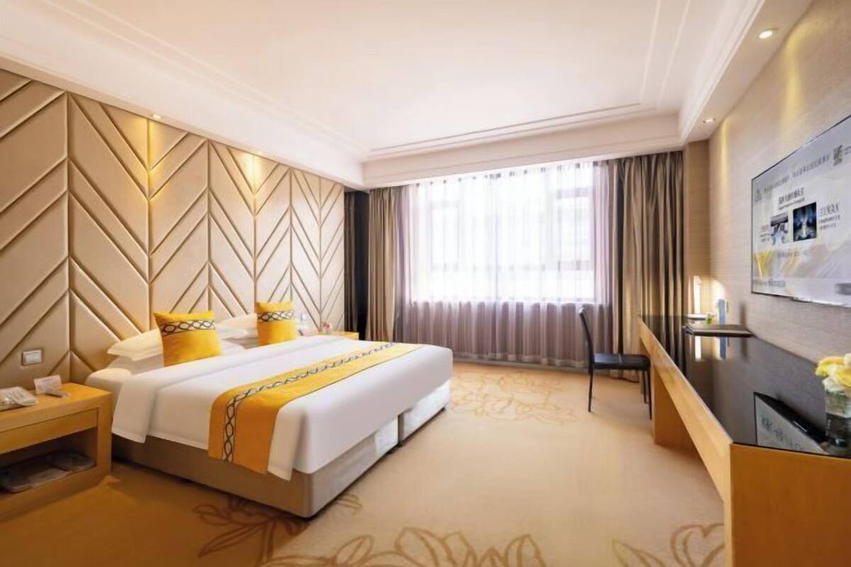 Una habitación de hotel con una cama grande, un escritorio y una televisión.