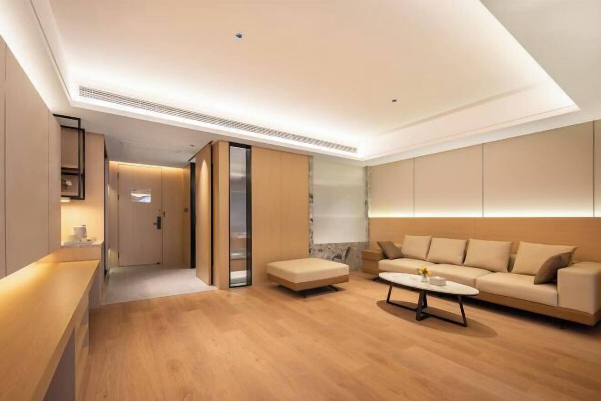 Una sala moderna con un sofá, una mesa de centro y un pasillo que lleva a una puerta.