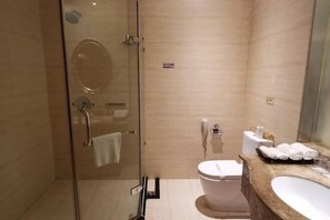 A modern bathroom with a glass-enclosed shower, a toilet, and a sink with a marble countertop. - Faguo Hotel (Dalian)