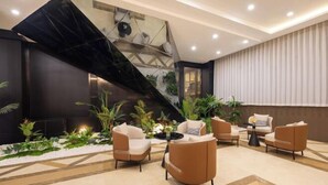 A modern lobby with a geometric black wall, a staircase, and a seating area with beige and brown chairs. - Faguo Hotel (Dalian)