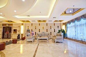 A spacious lobby with a high ceiling, ornate furniture, and a large window with curtains. - Faguo Hotel (Dalian)