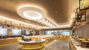 A modern hotel lobby with a central reception desk, a staircase, and a buffet area. - Faguo Hotel (Dalian)