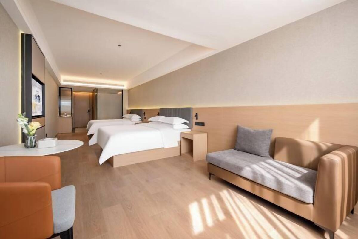 Una habitación de hotel moderna con una cama grande, un sofá y un escritorio con una silla.