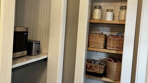 A small pantry with shelves containing jars, baskets, and a toaster. - The Kohler House (Kohler)