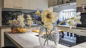 Eine Küche mit weißen Schränken, einem Herd und einer Vase mit weißen Blumen auf der Arbeitsplatte.
