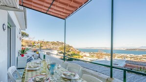 A balcony with a table set for dining, overlooking a coastal town and the sea. - Cozy apartment in Ischia with WiFi (Ischia)