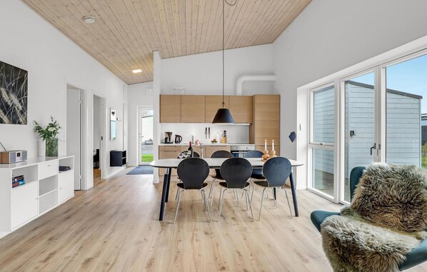 Une cuisine moderne avec des meubles en bois, un coin repas comprenant une table et des chaises, et une grande porte-fenêtre coulissante donnant sur un balcon.