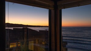 A view from inside a building looking out to the sea at sunset. - Coastal Luxury: Oceanfront Views, Decks + Walkable to Downtown (Monterey)