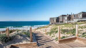 A wooden boardwalk leading to a beachfront property with multiple wooden buildings. - Coastal Luxury: Oceanfront Views, Decks + Walkable to Downtown (Monterey)