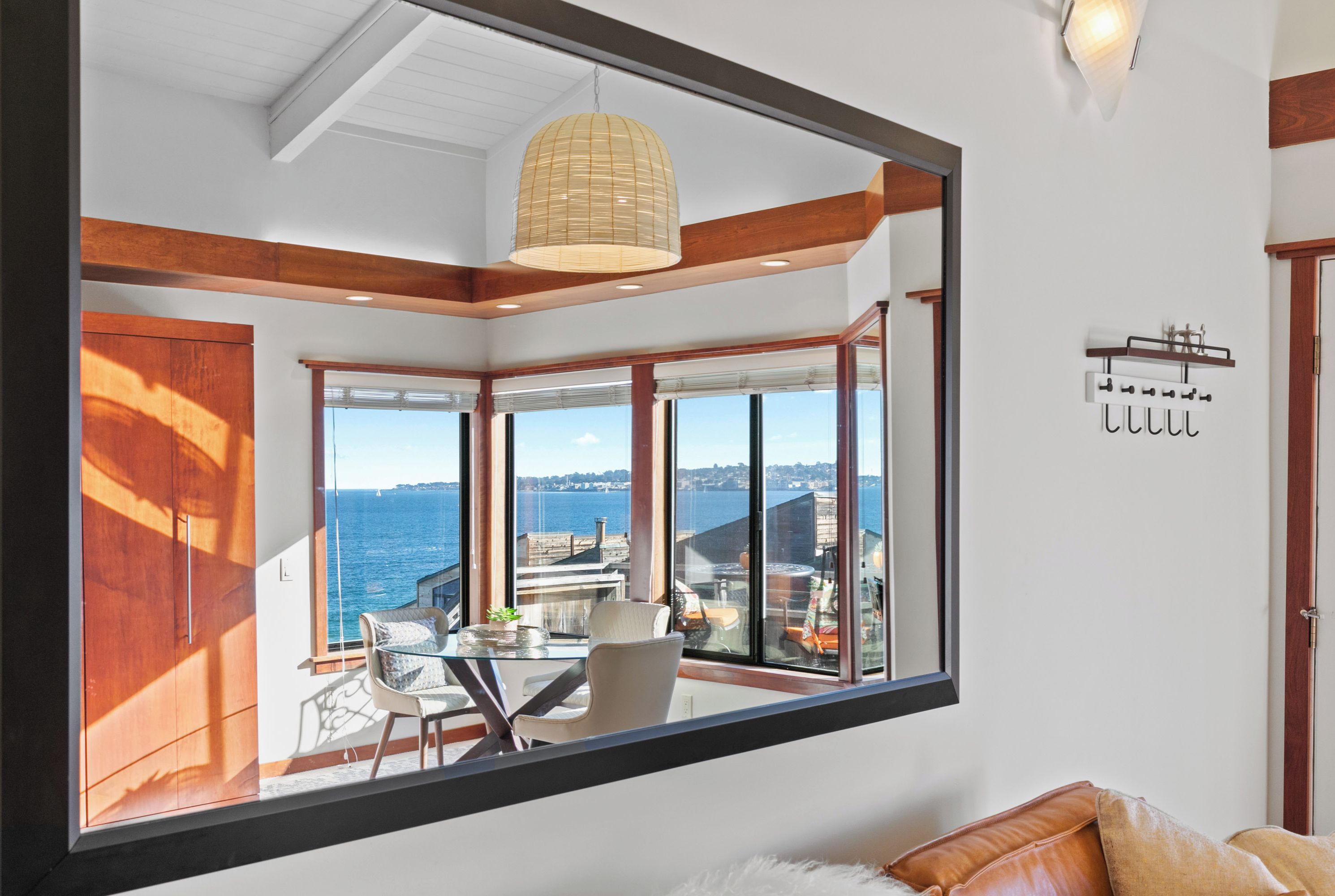 A modern room with large windows, a dining area, and a view of the sea.