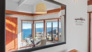 A modern room with large windows, a dining area, and a view of the sea.