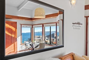A modern room with large windows, a dining area, and a view of the sea.