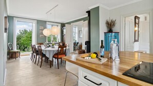 Une cuisine moderne avec des plans de travail en bois, une cuisinière encastrée et un coin repas offrant une vue sur la verdure.