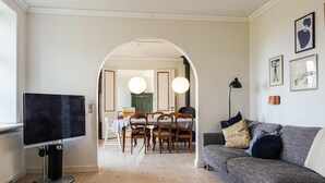 Un salon comprenant un téléviseur, un canapé et un coin repas avec une table et des chaises.