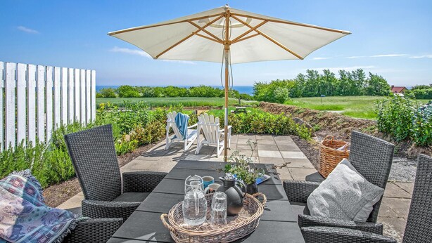 A patio with wicker furniture, a table with drinks, and a large umbrella. - Gorgeous apartment in Nexø with WiFi (Nexø)