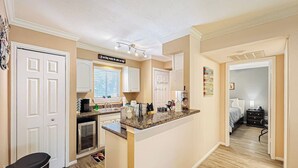 A modern kitchen with a central island, white cabinetry, and a dining area visible through an open door. - Lakefront Action | Paddle • Pickle • Pool • Sunset (Montgomery)