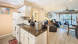 A modern kitchen with white cabinets, a granite countertop, and a dining area with a table and chairs. - Lakefront Action | Paddle • Pickle • Pool • Sunset (Montgomery)